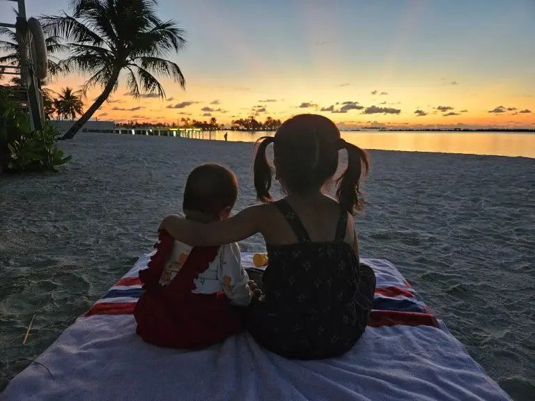 Two babies in silhouette watching a sunset over the ocean in the Maldives, highlighting the serene beauty of the islands